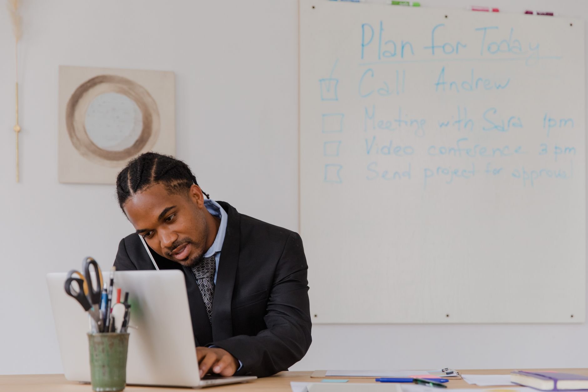 Businessman at his desk juggling phone calls and laptop, representing the challenge local business owners face responding to customers